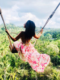 Rear view of woman with arms raised against sky