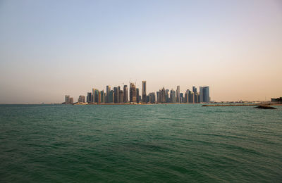 Scenic view of sea and buildings against clear sky