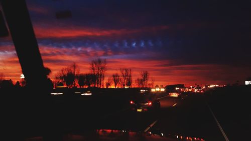 Silhouette cars on road against sky at night
