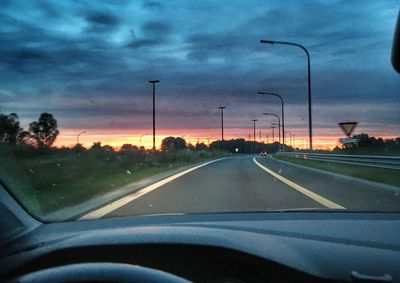 Road seen through car windshield during sunset