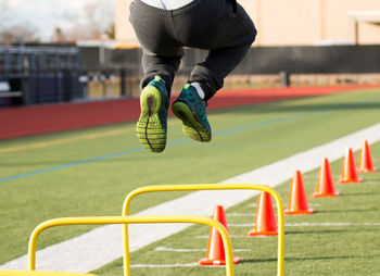 Low section of person jumping across fence in playground