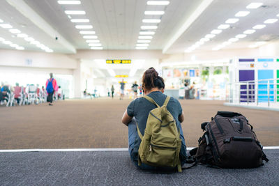 Rear view of woman sitting at airport