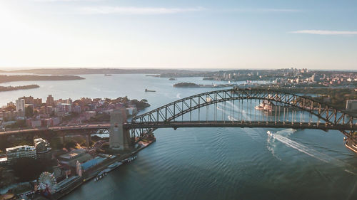 Arch bridge over river amidst buildings in city against sky