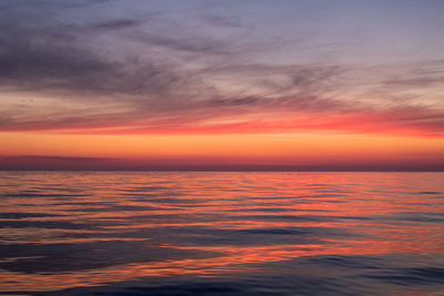 Scenic view of sea against dramatic sky during sunset