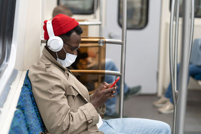 Rear view of man using mobile phone in train