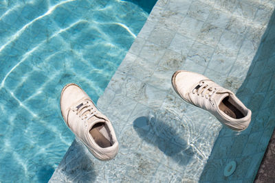 Adult sneakers swim in the pool. shoes falling in swimming pool water