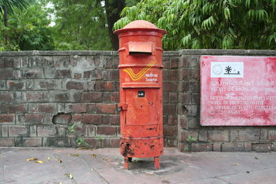 Old mailbox on sidewalk against retaining wall