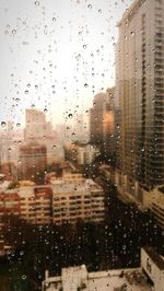 Buildings seen through wet glass window during rainy season