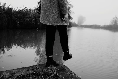 Low section of woman standing by lake against sky