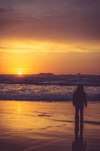 Silhouette man standing at beach during sunset