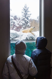 Rear view of people on glass window during winter