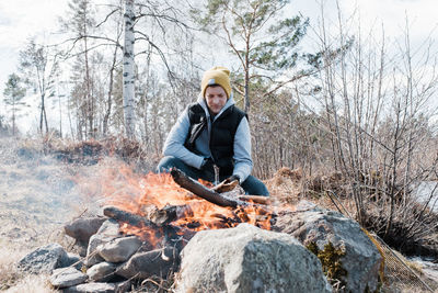 Man sat next to an outdoor fire whilst camping