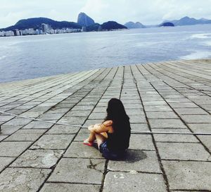 Rear view of young woman sitting on promenade