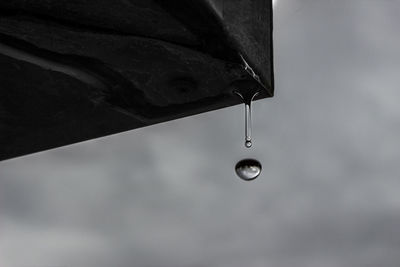 Low angle view of water drop falling against sky