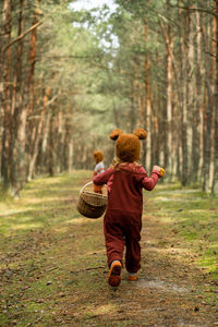 Toddler baby twins in bear bonnets playing and having fun in the woods