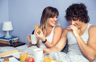 Couple having breakfast on bed at home
