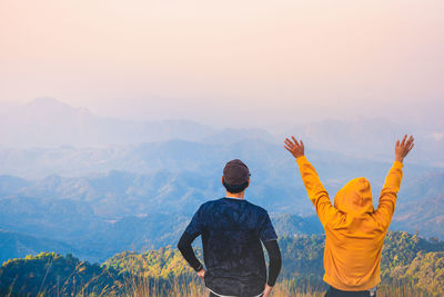 Rear view of men looking at mountains against sky on wanderlust trip in summer