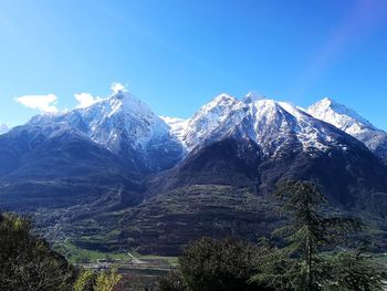 Scenic view of snowcapped mountains against blue sky