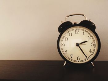 Close-up of clock on table against wall