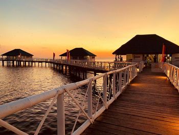 Pier over sea against clear sky during sunset