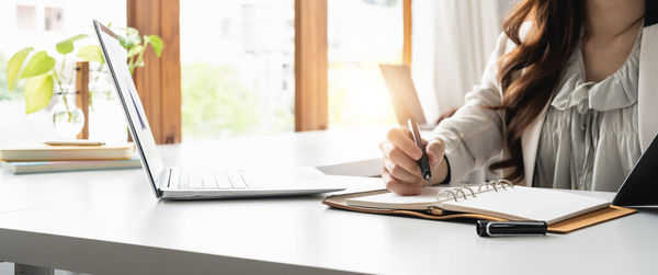 Midsection of businesswoman working on table