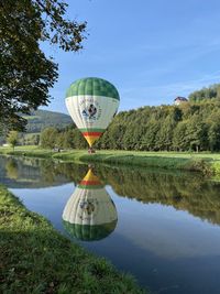 Hot air balloon in lake against sky