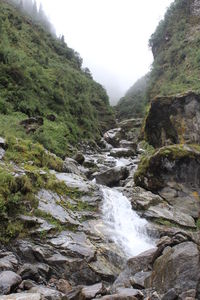 Scenic view of waterfall in forest against clear sky