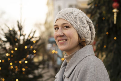 Contemplative woman with knit hat by christmas trees