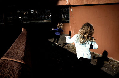 Rear view of girls running against wall