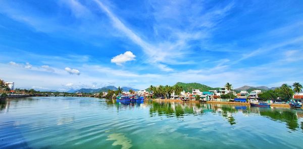 Scenic view of lake by buildings against blue sky