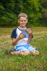 Full length of man using mobile phone in field