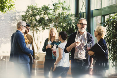 Multi-ethnic business people discussing while having juice in office