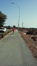 Rear view of man on road against clear sky