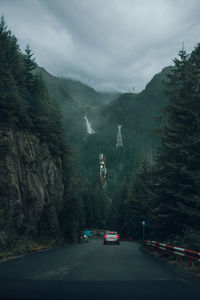 Cars on road by mountains against sky