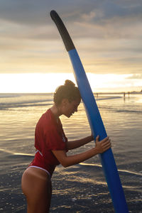 Tired woman after hard surfing session on the beach at sunset time