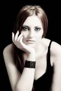 Portrait of beautiful woman with hand on chin against black background