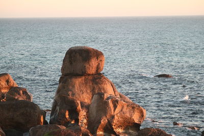 Rock formation in sea against clear sky