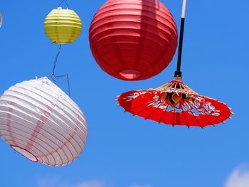 Low angle view of lanterns hanging against blue sky