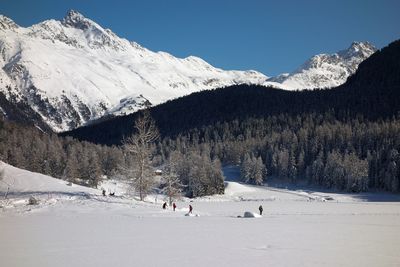 People walking on snow covered lake against sky