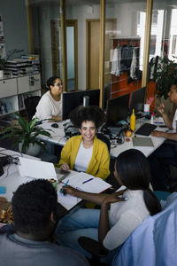 Happy female colleague discussing with coworkers at office