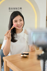 Young woman using mobile phone at table