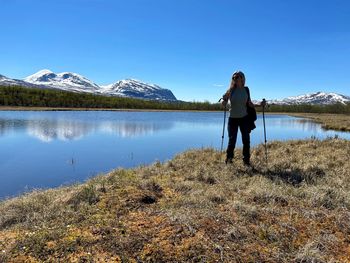 Full length of woman standing on lake by mountain against sky