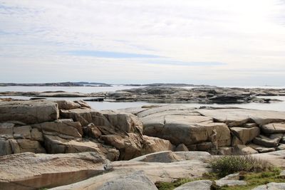 Scenic view of rocks by sea against sky