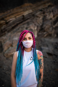 Portrait of woman wearing mask against rock formation