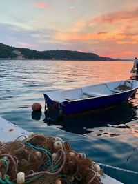 Boat moored in sea against sky during sunset