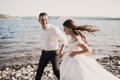 Side view of couple standing at beach