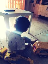 Rear view of boy playing toy at home