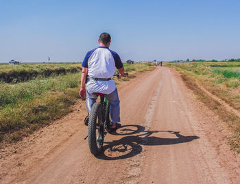 Rear view of man riding bicycle on road