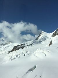 Low angle view of snowcapped mountains against blue sky