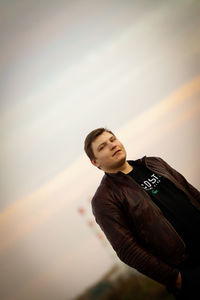 Low angle view of young man looking away against sky
